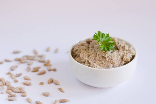 Photo of vegan spread made from sunflower seeds in the white bowl on the white background.