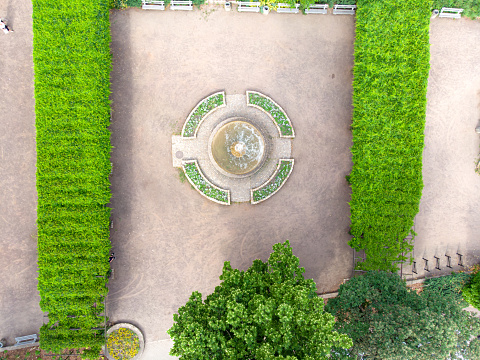 A view from a drone over green pergolas overgrown with ivy and a small fountain
