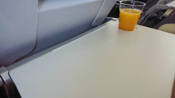 istock Plastic glass of orange juice on a folding table in the plane 1288314615