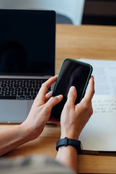 istock Close up Shot of an Anonymous Young Businesswoman's Hands Using a Mobile Phone while Working from Home on a Laptop 1288318053