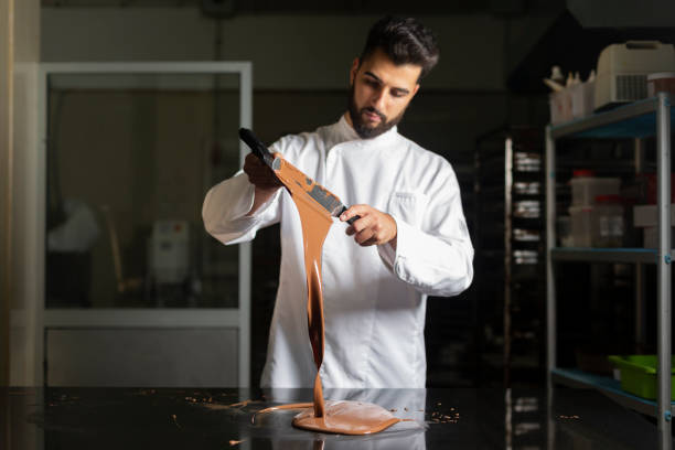 Pastry chef working on tempering chocolate on marble table Pastry chef closeup working on tempering chocolate on marble table confectioner photos stock pictures, royalty-free photos & images