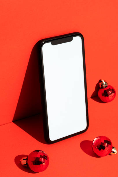 istock Blank white screen smart phone mockup, template on red background with Christmas balls 1288322441