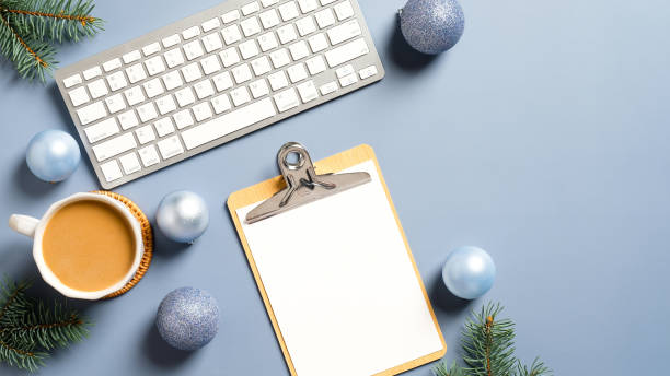 istock Office desk table with computer keyboard, paper clipboard, coffee cup and Christmas decorations on pastel blue background.Top view with copy space. Flat lay. 1288326062