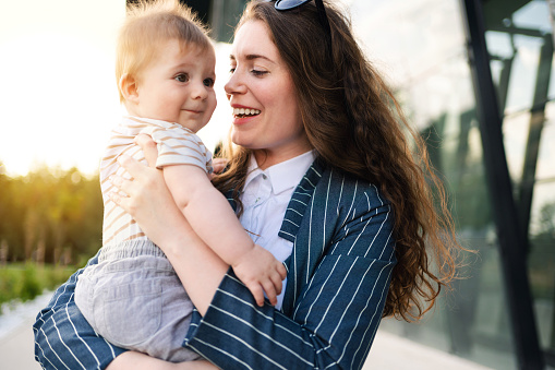 Young Caucasian mother with her baby outdoor.