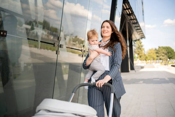 istock Young mom pushing a  stroller while carrying her baby boy 1288332004