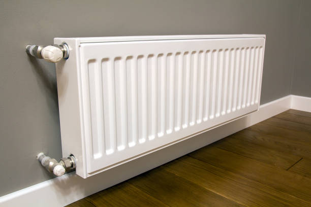 istock White metal heating radiator mounted on gray wall inside a room. 1288333842