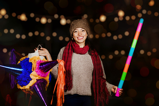 Mexican Woman Holding a colorful Piñata celebrating Christmas in a traditional Posada in Mexico City