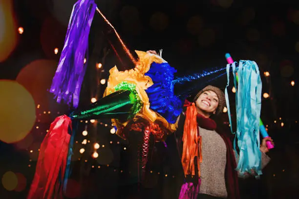 Mexican Woman Holding a colorful Piñata celebrating Christmas in a traditional Posada in Mexico City
