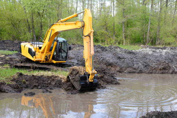 grande potente escavatore che scava canale di drenaggio nella palude in campagna - neumatic foto e immagini stock