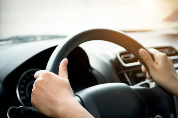 A woman's hand holding a car steering wheel,represents the correct car steering wheel. In order to prevent accidents.Show driving safe step.