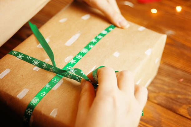 istock Women's hands tying ribbon on Christmas gift. 1288363262