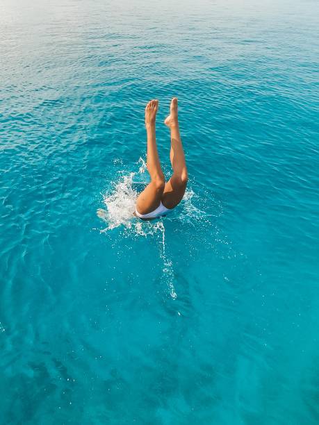 istock Woman in a bikinis jumping into the clean water 1288366641