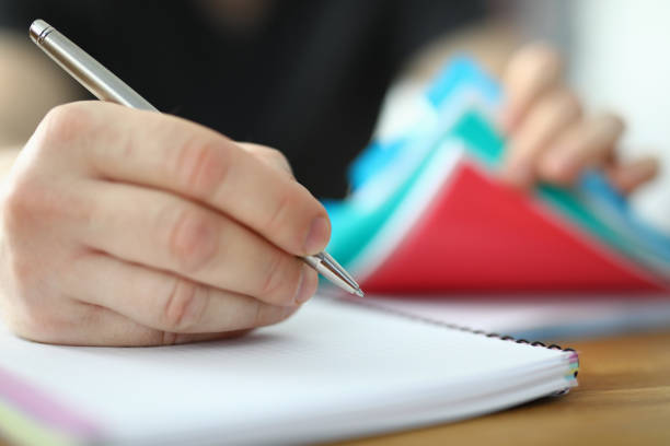 istock Man holds pen in his hand and writes in notebook 1288368344