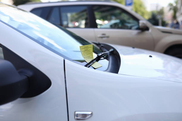 Yellow document on machine Close-up of white automobile with parking ticket under windshield wiper. Auto on street. Penalty charge notice paper. Luxury vehicle. Illegal and law concept traffic fine stock pictures, royalty-free photos & images