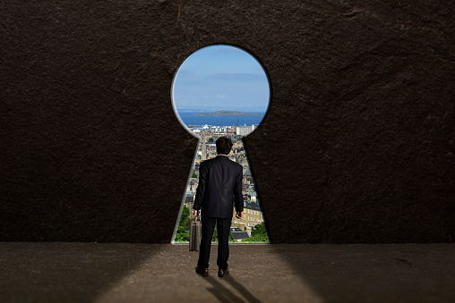 A businessman thinking business concept in front of a huge keyhole, Concept of finding the way.