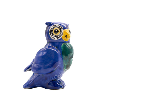 Blue owl (Strigiformes) made of clay and painted, handcrafted. copy space. isolated on white. Side view.