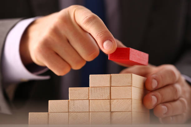 istock Man arranging wood block and stacking as tower by hand 1288374814