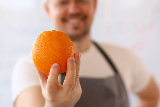 istock Happy mature man is holding orange fruit 1288375623