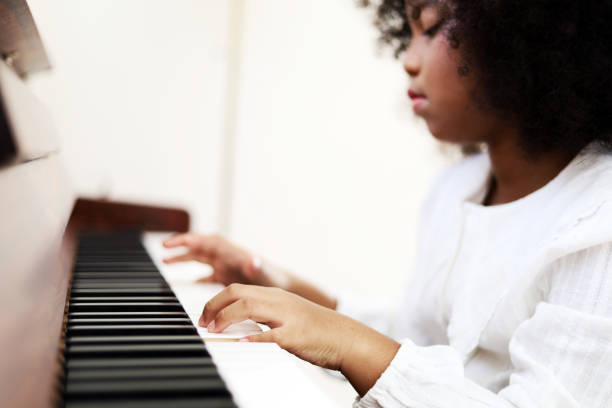 bela garota africana tocando teclado de piano na sala de aula aprendendo na sala. - sheet music music classroom education - fotografias e filmes do acervo