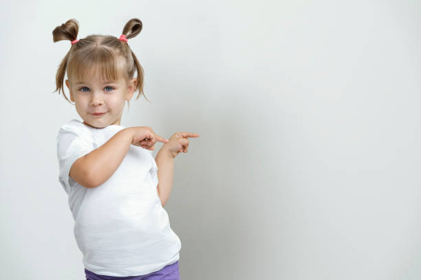 süße mädchen zeigt auf den hintergrund hinter sich selbst. mock-up für ihr design - baby pointing child showing stock-fotos und bilder