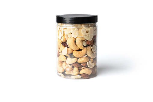 Various nuts (raisins, almonds, cashews, macadamia nuts) peeled and placed in a glass on a white background. with clipping path