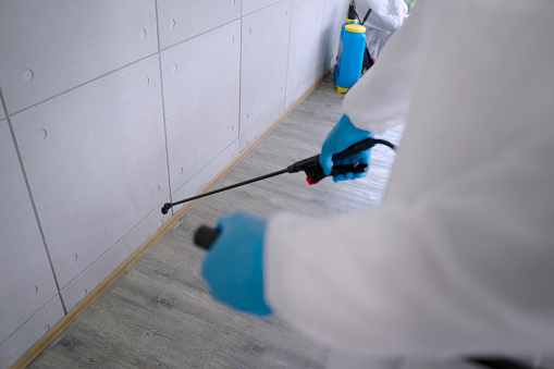 Staff spray germicide at the building and wear PPE suit for protection. Hygiene service concept.