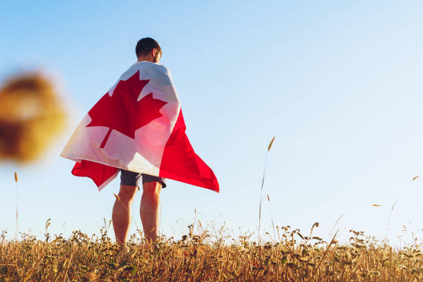 istock Man with a flag of Canada standing in field 1288383840
