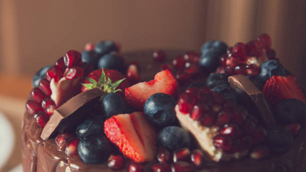 istock chocolate cake decorated with strawberries, blueberries and a pomegranate on an orange background 1288384765