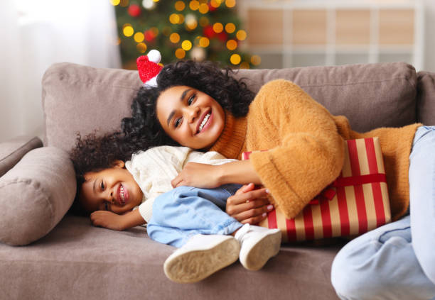 Cheerful ethnic family: happy child and mother congratulate each other at Christmas, playing and laughing Happy  ethnic african american family on holiday: cute kid boy and mother congratulate each other at Christmas, playing and laughing 15495 stock pictures, royalty-free photos & images