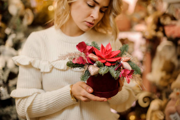 istock Bright creative flower arrangement decorated with golden Christmas tree decorations in woman's hand. 1288387895