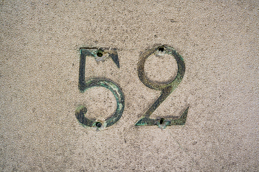 Weathered house number fifty two (52) on a stone wall