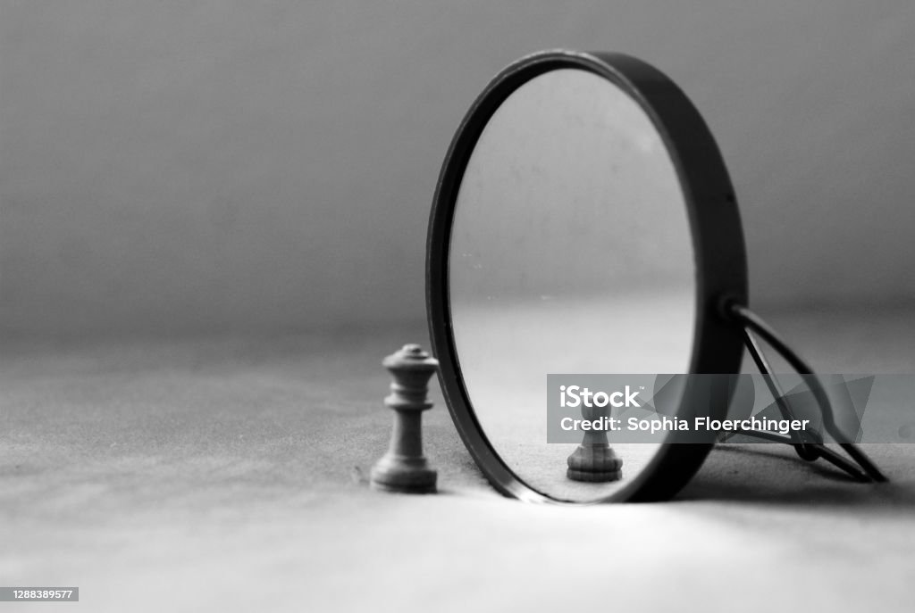 mirror image and self perception, insecurity lonely chess piece feeling small and insignificant Illusion Stock Photo