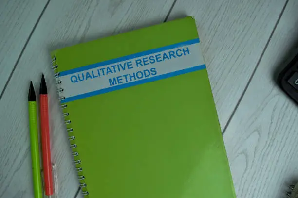 Qualitative Research Methods write on a book isolated on office desk.