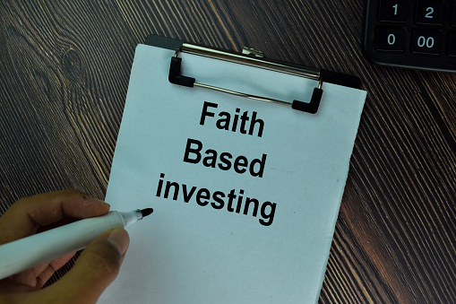 Faith Based Investing write on a paperwork isolated on wooden table.