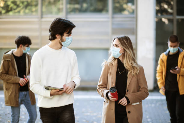 istock Happy college students, wearing a masks, walking together on campus 1288394284