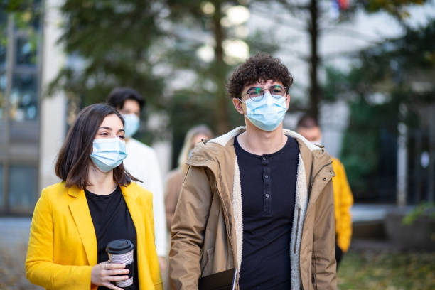 Happy college students, wearing a masks, walking together on campus stock photo