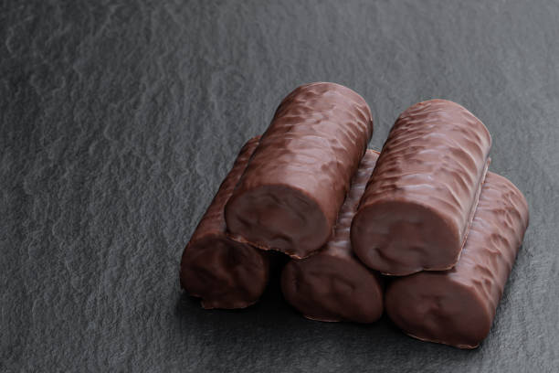 Chocolate sponge cake covered with milk chocolate on black stone background