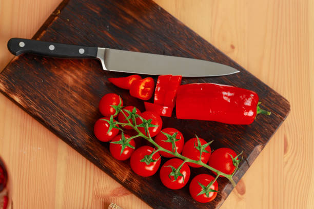 istock Wooden cutting board with cherry tomatoes and pepper on kitchen counter 1288401063