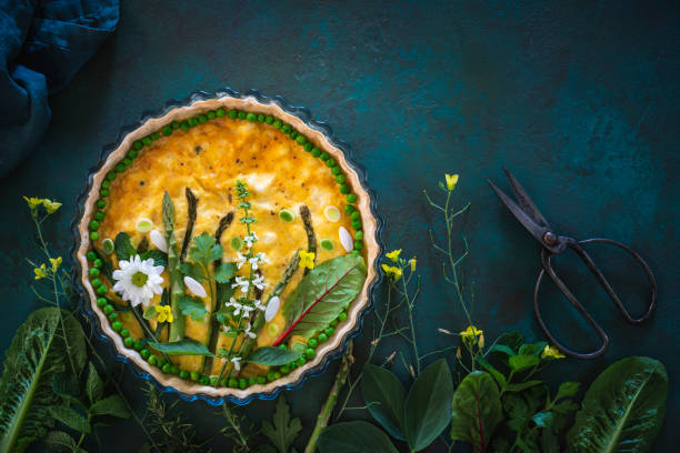 Quiche Lorraine savory tart vegan with raw vegetables creating a green garden Quiche Lorraine savory tart vegan with raw vegetables creating a green garden on a dark green background edible flower stock pictures, royalty-free photos & images