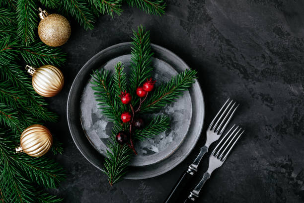 istock Christmas dinner background with empty plate and gold decor on dark table. 1288407273