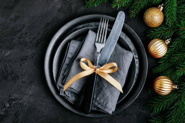 istock Christmas dinner background with empty plate and gold decor on dark table. 1288407282