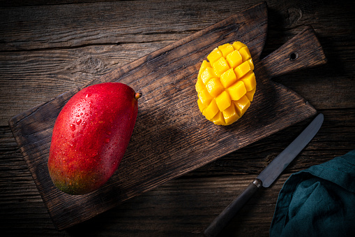 Red mango fruit in rustic wooden table background and cut mango fruit on cutting board and knife