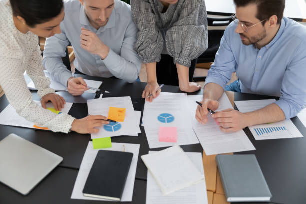 istock Top view focused young serious multiracial teammates doing paperwork. 1288408833
