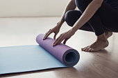 Woman rolling up exercise mat and preparing doing yoga or fitness