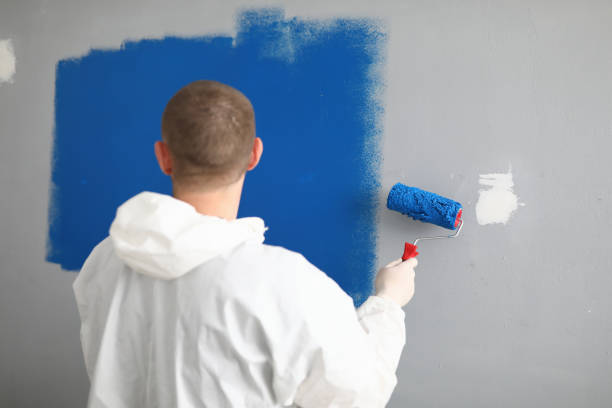 istock Man with roller in his hands paints wall in blue. 1288409896