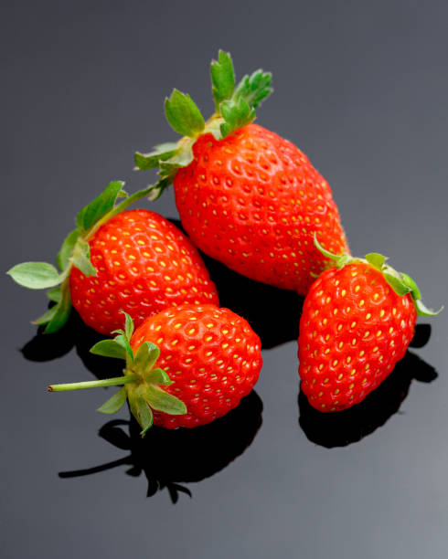 istock Macro image of fresh red strawberries group isolated at black background with reflection. 1288410392