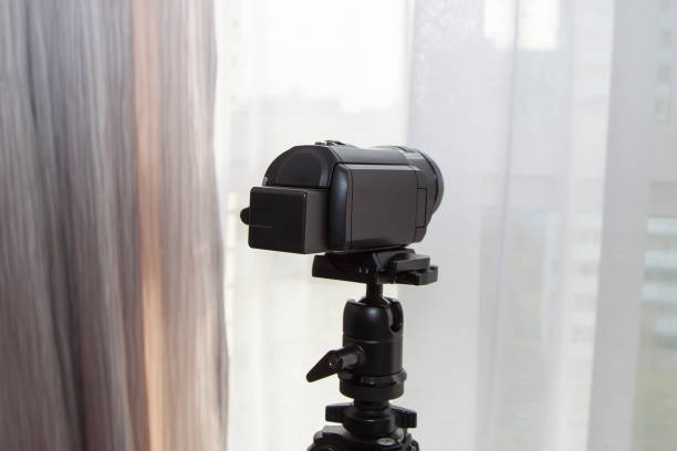 caméra vidéo sur trépied est destiné à la fenêtre pour espionner les résidents de la maison en face - photographer camera tripod paparazzi photographer photos et images de collection