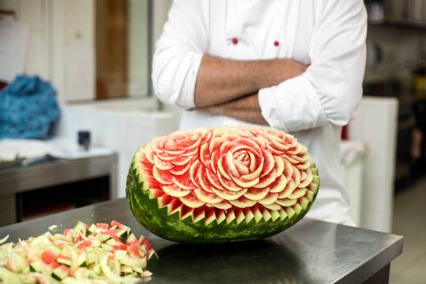 Food carving Chef carving a watermelon in a kitchen. Unrecognizable person, Caucasian male. carving fruit stock pictures, royalty-free photos & images