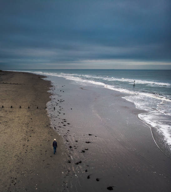 homme seul regardant dehors à la mer avec des vagues s’écraser et le ciel moody - witterung photos et images de collection