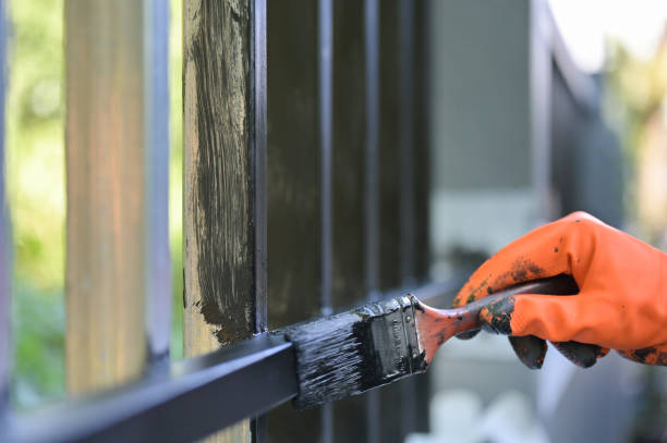 Worker painting steel with paint brush and orange gloves selective focus on hand. stock photo